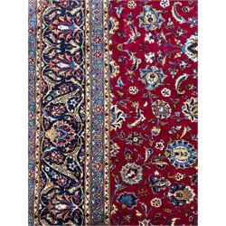 Northeastern Persian Meshed hand-knotted carpet, madder red field with an all-over design of scrolling vines, palmettes, and rosettes, within a dark blue border of palmettes and arabesques 