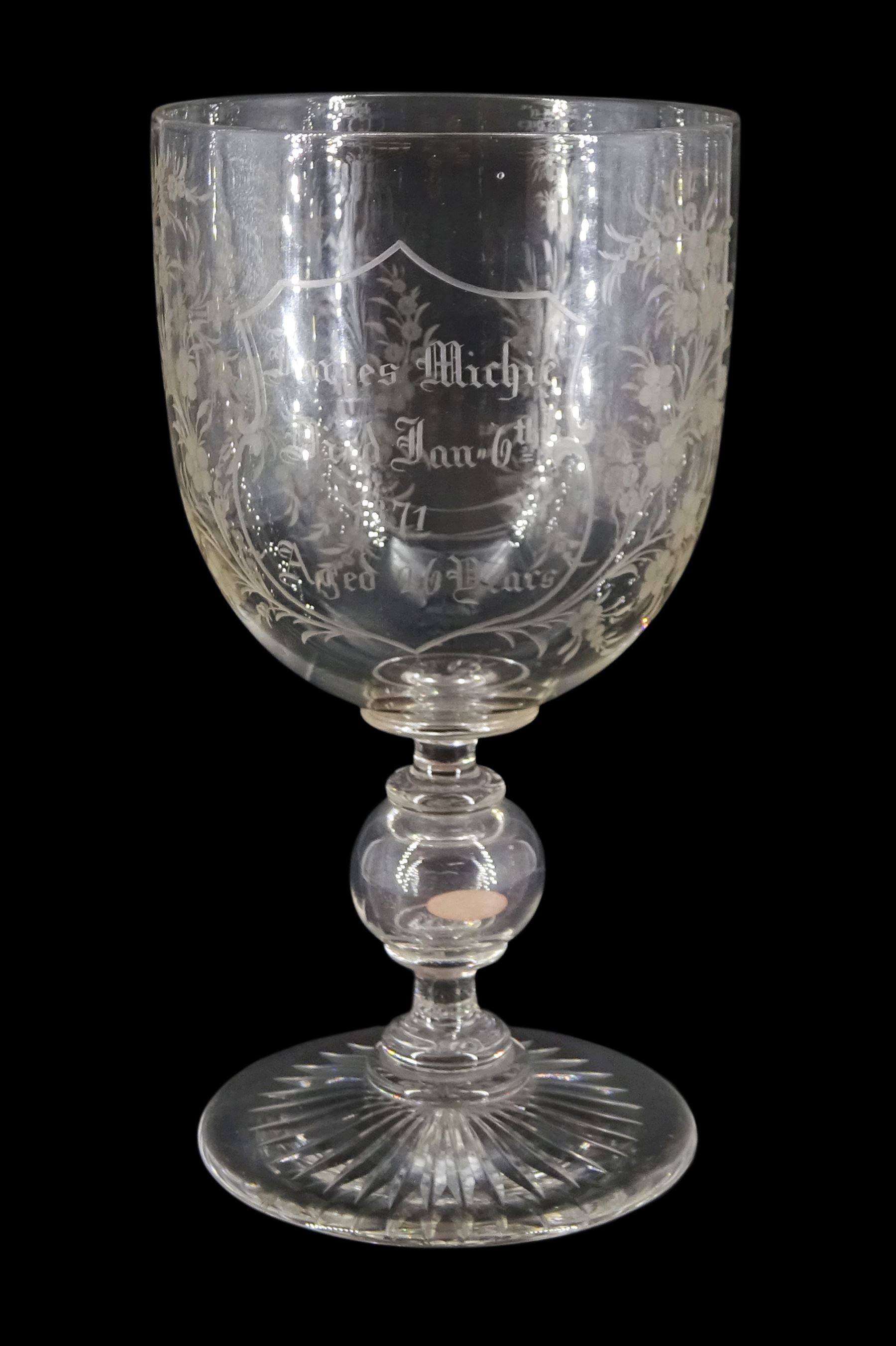 Late 19th century oversized glass goblet, the bowl engraved with cartouche containing dedication 'Jams Michie Died Jan 6th 1871 Aged 26 Years', surrounded by foliate detail, upon a hollow knopped stem containing a silver Victorian 1861 threepence and circular foot with star cut base, H19.5cm