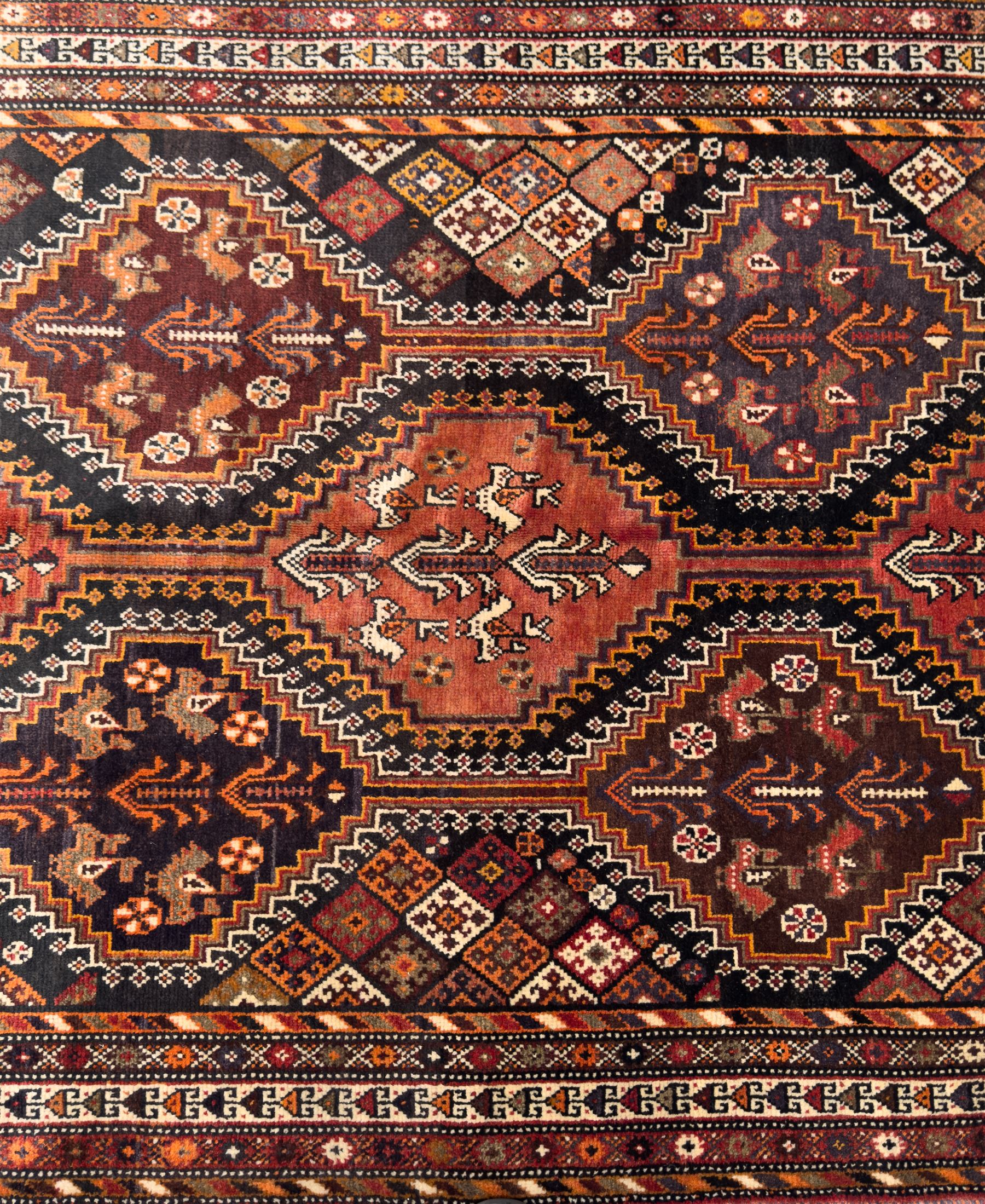 Southwestern Persian Qashqai hand-knotted carpet, the field with a lattice of hexagonal medallions in rust, indigo, and ochre, each containing stylised tree and floral motifs, flanked by lozenge panels with geometric designs, enclosed by multiple borders with rosettes and leaf motifs