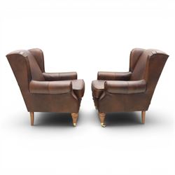 Marks & Spencer - Pair of brown leather wing back chairs, raised on light stained supports with castors