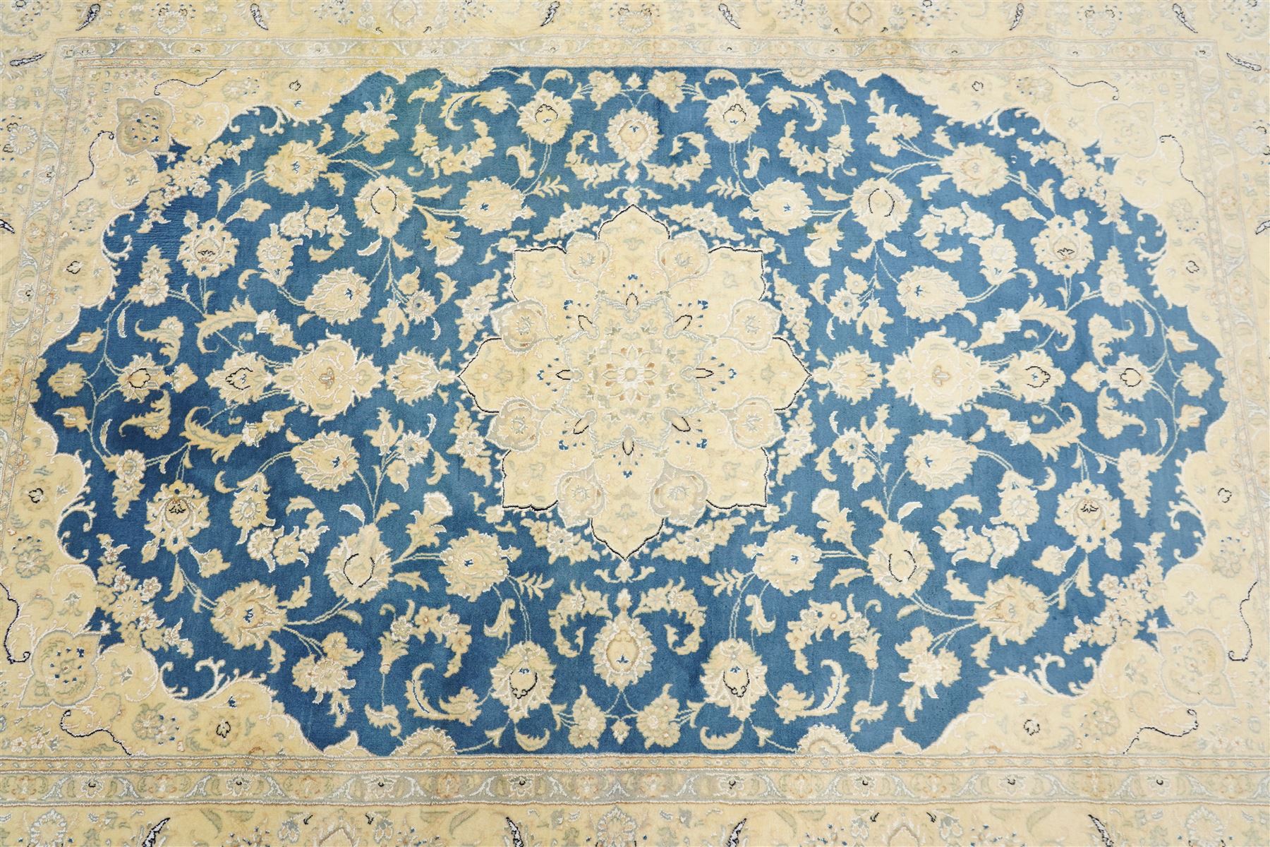 Central Persian Nain hand-knotted rug, sky blue field, with a central cusped medallion in ivory and soft camel tones, issuing an elegant arrangement of scrolling arabesques, palmettes and flowering vines, conforming ivory spandrels, principal pale border decorated with floral sprays and palmettes, flanked by narrow ground borders, with cotton fringe ends  