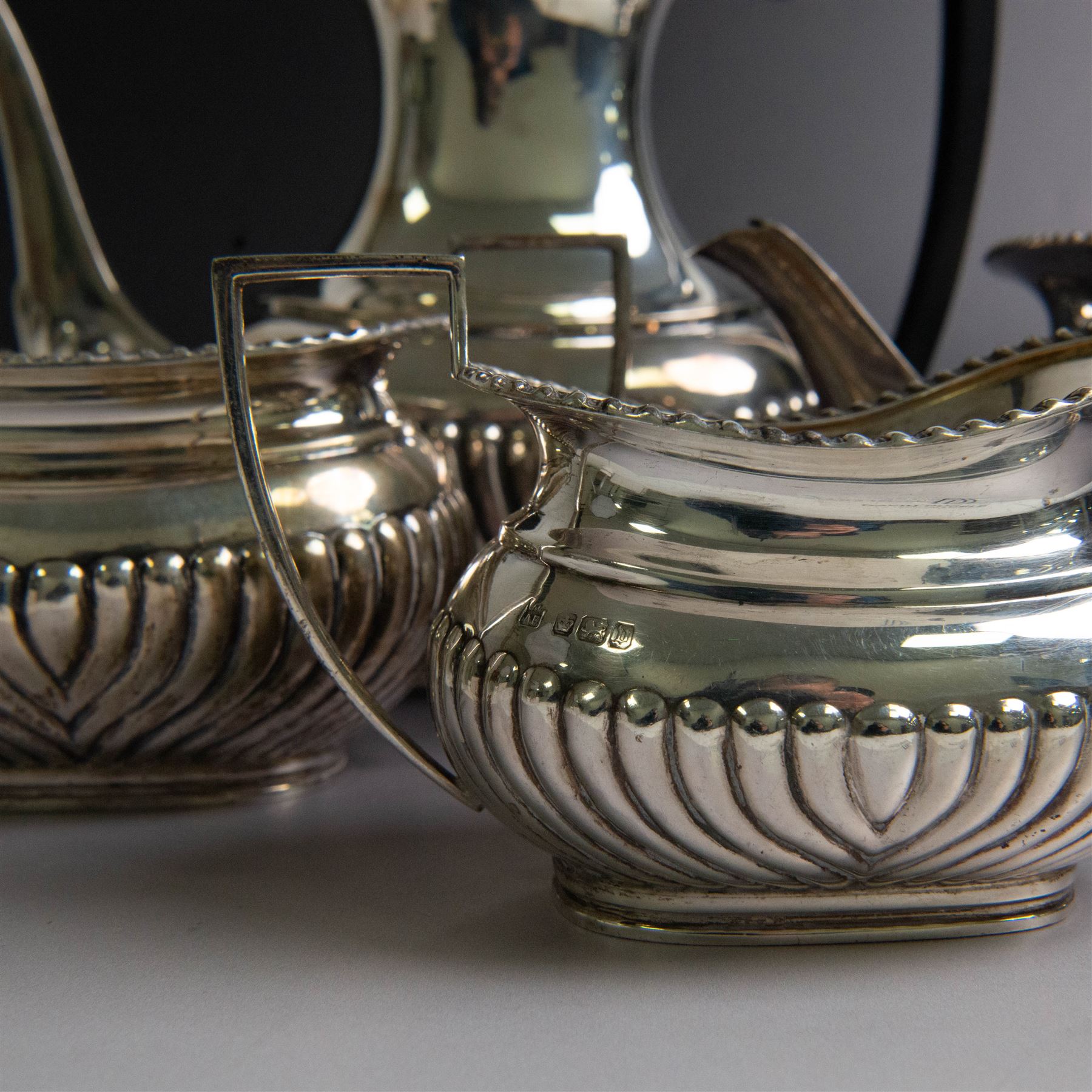 Edwardian silver four piece tea service, comprising coffee pot, teapot, twin handled open sucrier and milk jug, all of oval bellied form, part fluted and with oblique gadrooned rim, with Bakelite type handles and finials to teapot and coffee pot, hallmarked Fordham & Faulkner, Sheffield 1913