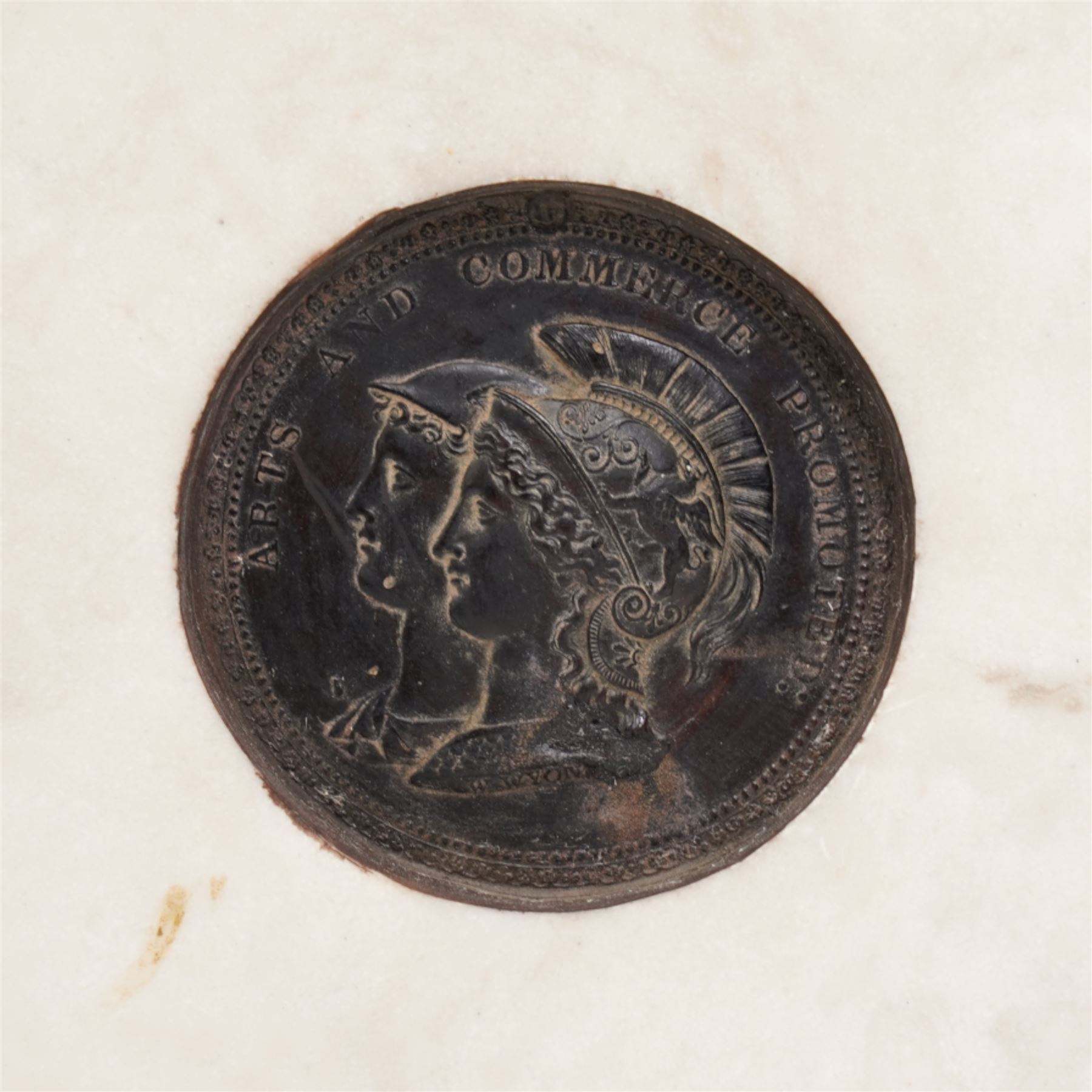 Composite plaque, depicting Sprites in a garden, with inset 'Arts and Commerce Promoted' medallion to reverse, 20cm x 33cm; together with a moulded glass Claret jug with silver plated mount H30cm 