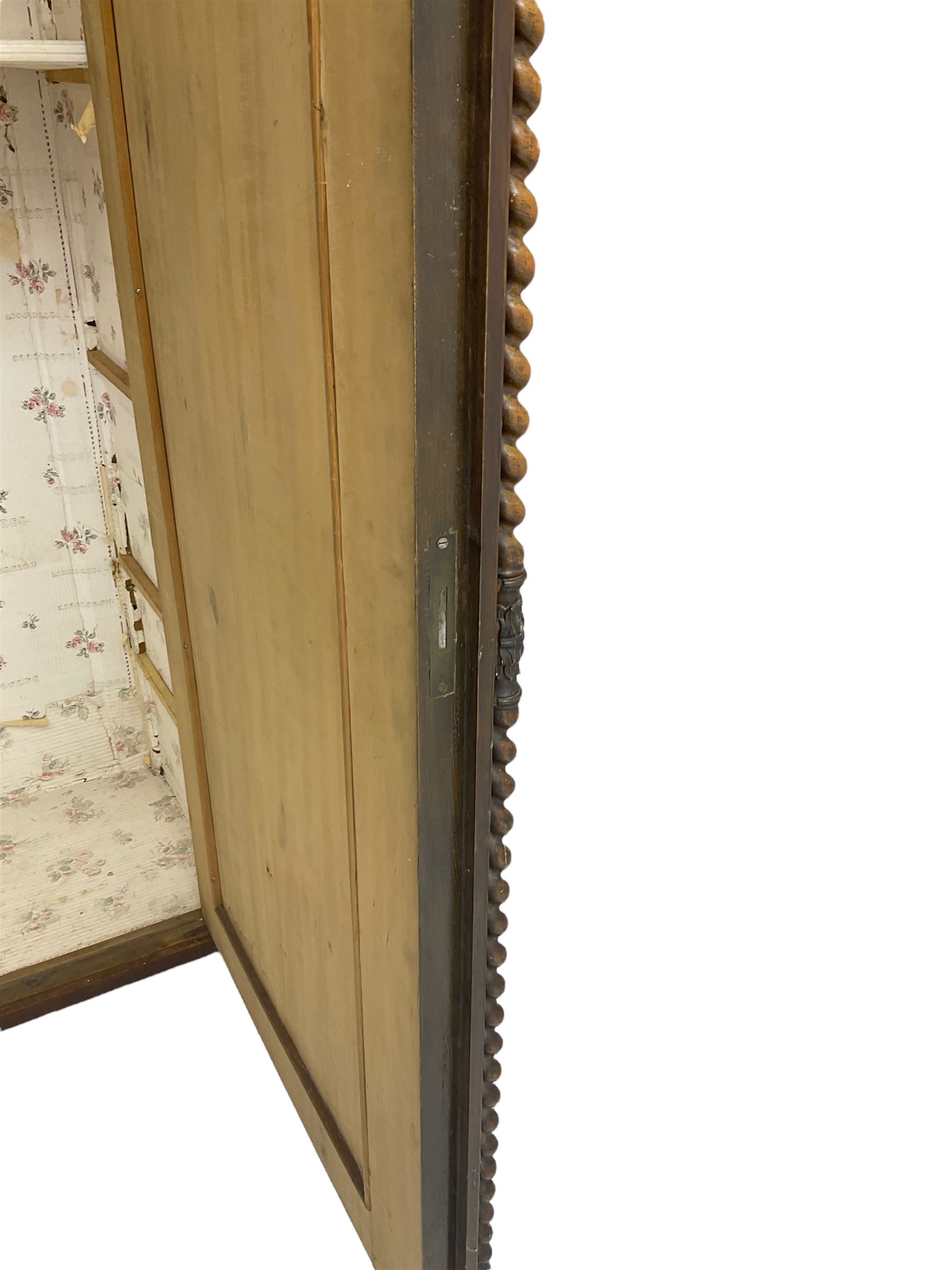 Early 20th century Italian walnut armoire wardrobe, the pierced and scrolling pediment carved with acanthus leaf detail, flanked by two scrolling cartouche with matching corbels below, the two panelled doors with applied carved rinceaux slips, with a central spiral turned upright, enclosing single shelf and hooks, raised on scroll feet