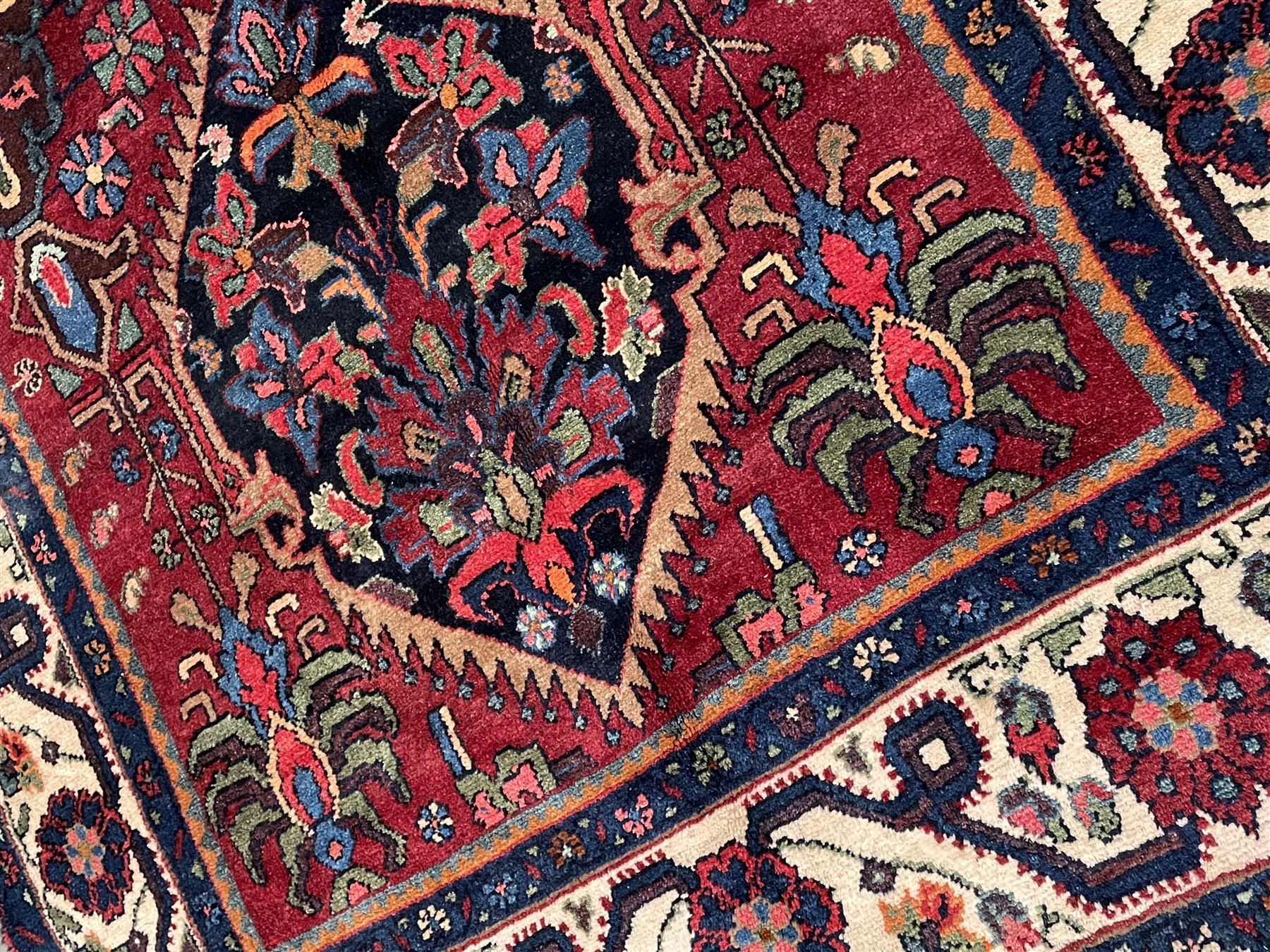 Persian Hamadan rug, the red ground field decorated with two floral medallions and stylised flower heads, repeating guarded border