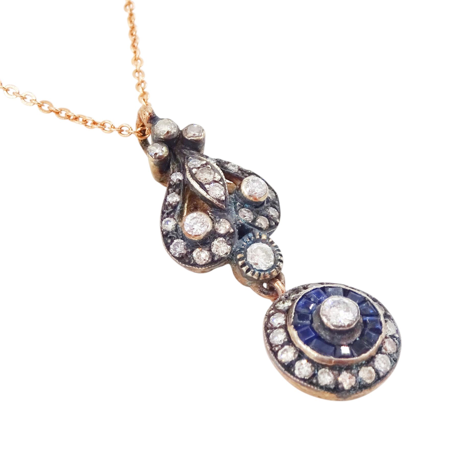 Gold and silver sapphire and diamond pendant, single round brilliant cut diamond, surrounded by calibre cut sapphires and round brilliant cut diamonds, suspending from a fancy pendant set with further diamonds, on a rose gold plated silver chain necklace, total diamond weight approx 0.60 carat