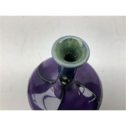 Three Minton Secessionist vases, with tube-lined stylised flower decoration, two upon a red ground and third upon a purple ground, all with printed mark to base 'Minton Ltd, No. 33', H13cm