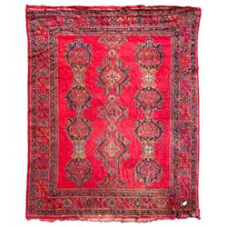 Early 20th century Western Anatolia Turkish Oushak crimson ground carpet, the field decorated with rows of Herati and Palmette medallions, the main border decorated with stylised flower head motifs within guard stripes