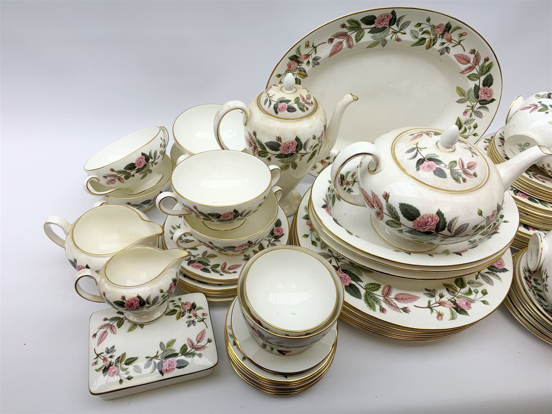 Wedgwood Hathaway Rose pattern dinner and tea wares, comprising eight dinner plates, eight salad plates, eight dessert plates, six side plates, six soup bowls and six saucers, sauce boat and stand, three oval serving dishes, oval serving platter, teapot, coffee pot, eight tea cups and eight saucers, eight coffee cans and eight saucers, two open sucriers, milk jug, cream jug, two ashtrays, and a lidded box and cover. 