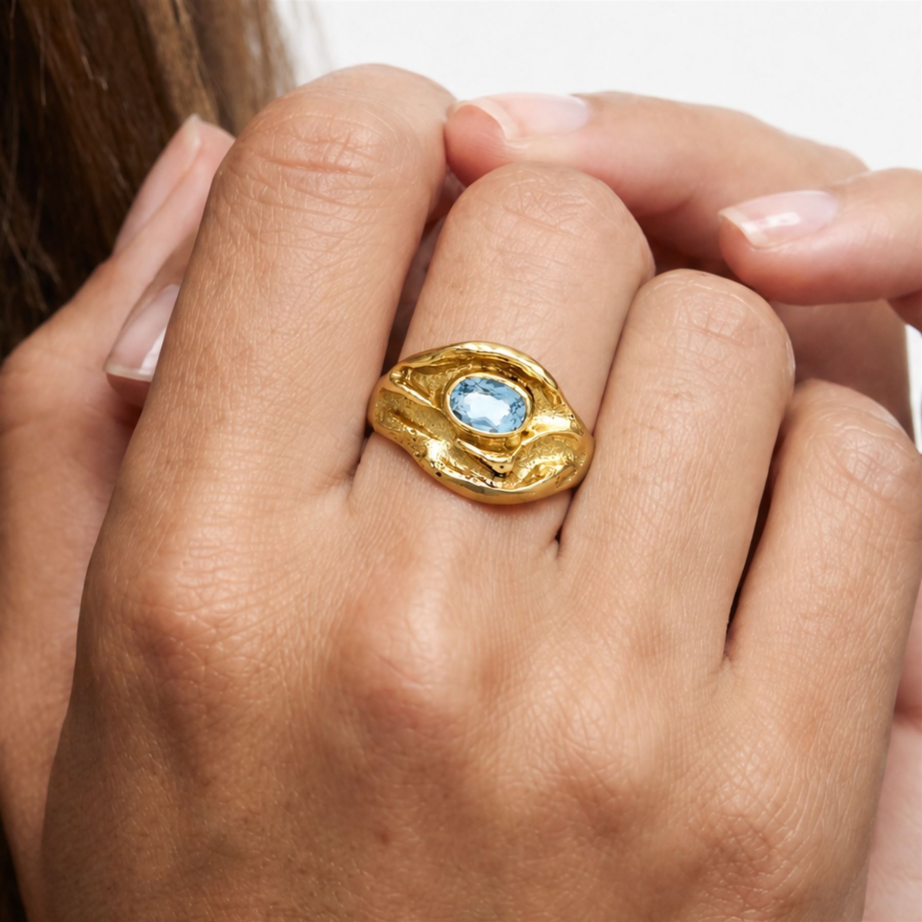 18ct gold Swiss blue topaz ring, bezel single oval cut topaz, within an abstract creased design setting, stamped 750