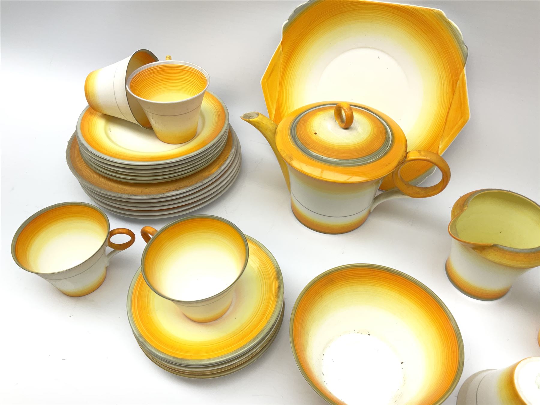 A Shelley Art Deco tea service, decorated in pattern no W12405, with bands of grey, orange and yellow, comprising teapot, open sucrier, milk jug, cake plate, six teacups, six saucers, six side plates, and six dessert plates. 