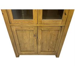 Tall oak cabinet, fitted with two glazed doors over two panelled cupboards, on square feet