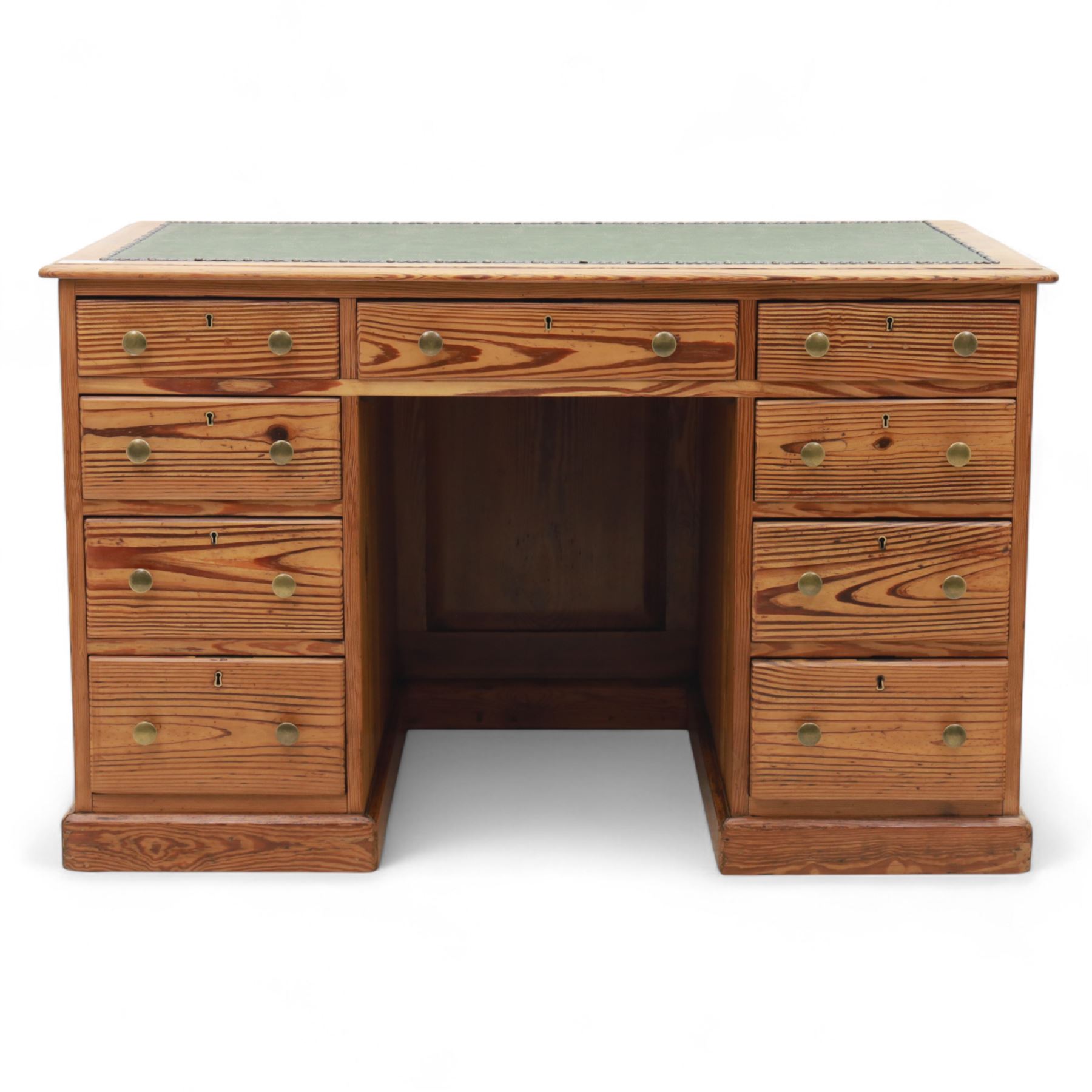 Contemporary stripped and waxed pine pedestal kneehole desk, rectangular top inset with green leather writing surface with brass studded edge, fitted with nine drawers with brass knob handles, above a plinth base on recessed castors