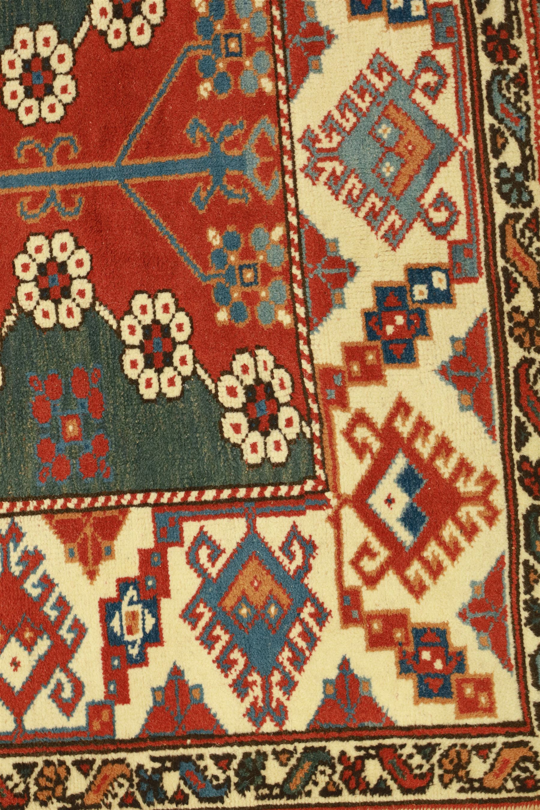 Caucasian Soumak rug, red madder field and teal panels, with bold stepped diamond medallion with hooked motifs and cruciform devices, and floral rosette clusters, surrounded by an ivory border with large hooked diamonds and stylized ram's horn devices, flanked by narrow guard stripes




