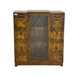Art Deco burr walnut drinks cabinet, geometric central glazed astragal door enclosing two fixed shelves, flanked by symmetrical bookmatched veneered cupboards with drawers above 