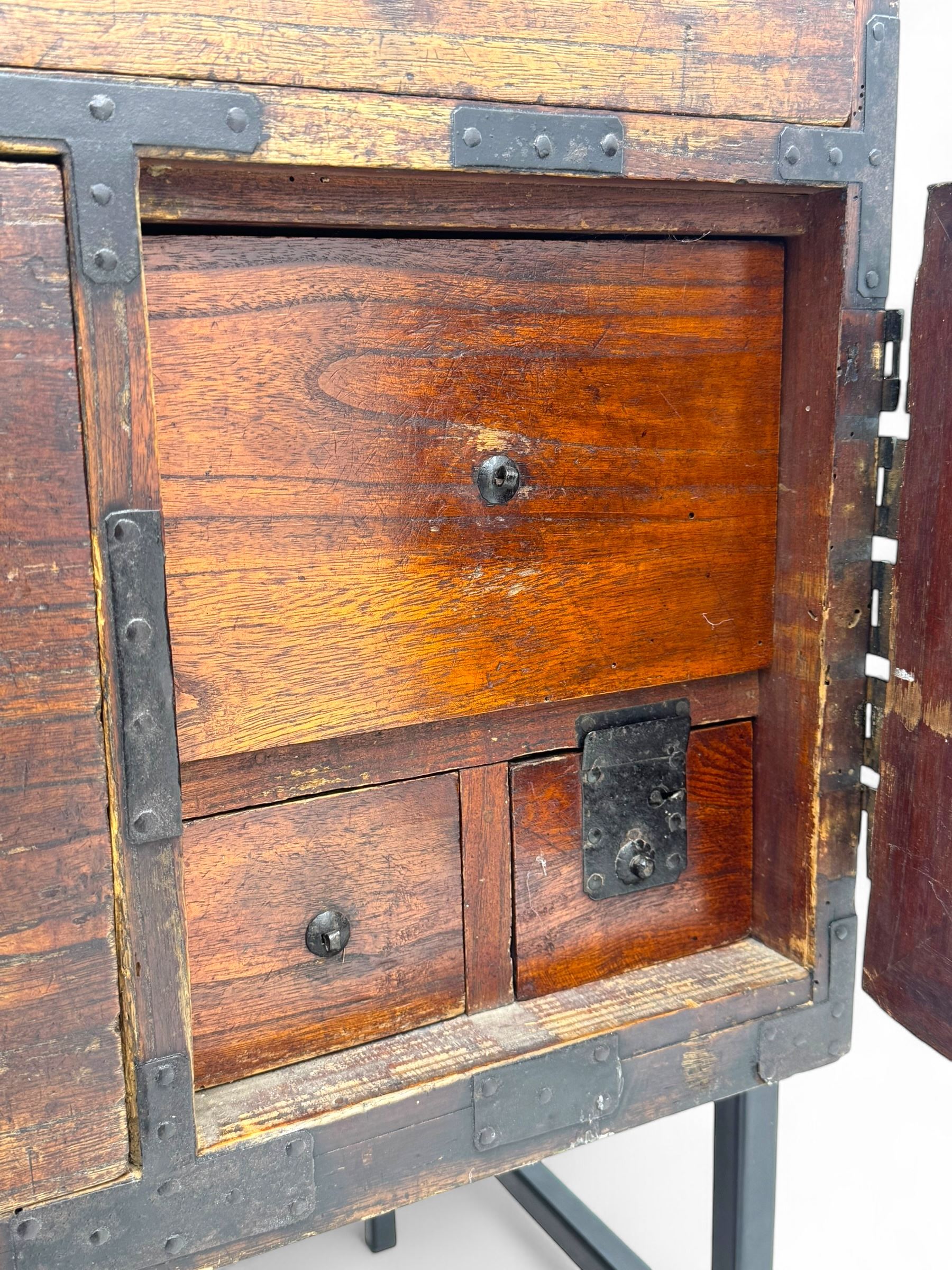 Late 19th century Japanese tansu chest, crafted with a cedar frame and cypress wood panels, original iron fittings throughout, comprising a single long drawer above smaller drawer and hinged cupboard door enclosing two smaller internal drawers and storage compartment, mounted on a bespoke black metal stand