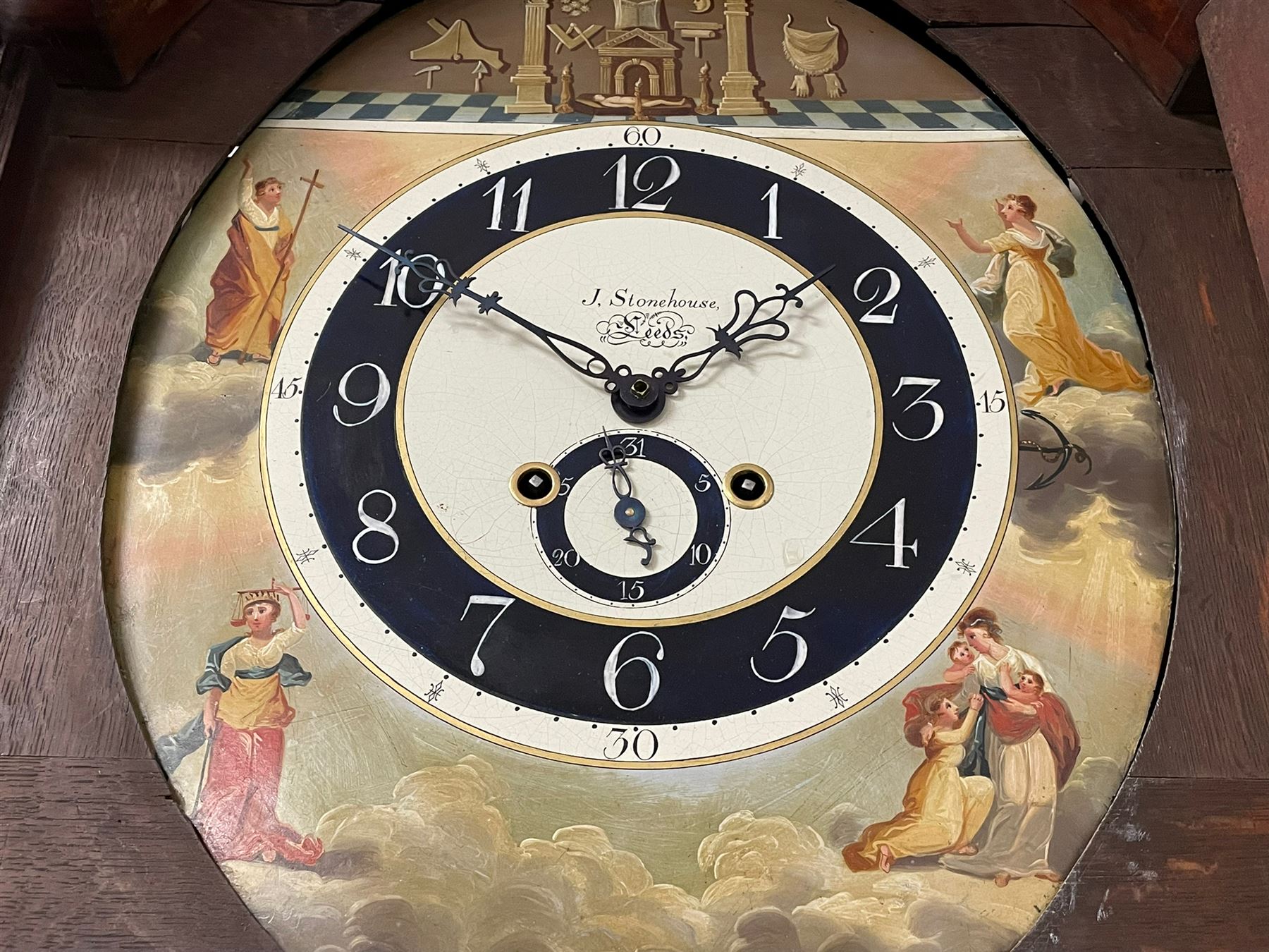John Stonehouse of Leeds - mahogany 8-day longcase clock with a painted oval dial c1830, hood with a swans necked pediment and profuse contrasting inlay to both the hood and case, oval hood door with flanking pilasters and Corinthian capitals, conforming case with canted corners and short triple spire door, broad plinth with matching inlay and canted corners on shallow base, dial depicting masonic regalia, symbols, and pictorial depictions of the humanities, faith, hope, charity and righteousness, black chapter with white roman Arabic’s, date recorder and matching “crown” hands, dial pinned to a rack striking movement with a recoil anchor escapement, striking the hours on a coiled underslung gong. With weights and gridiron pendulum. 
This clock case is of large, impressive dimensions and was almost certainly commissioned for a large masonic lodge in Leeds, a rare and unique example.