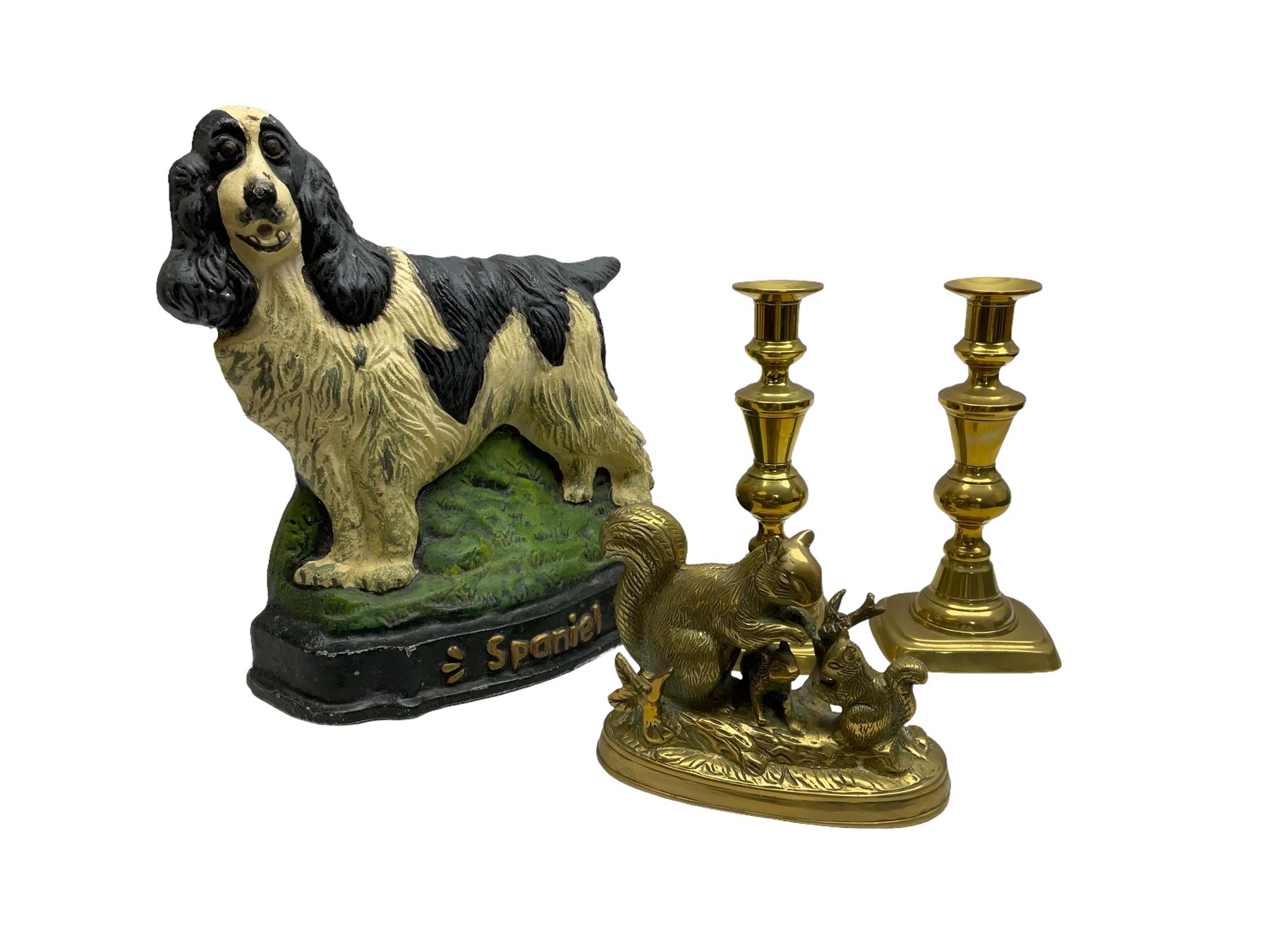 Cast iron doorstop modelled as a spaniel dog on grassy base, together with brass squirrel family group and pair of brass candlesticks