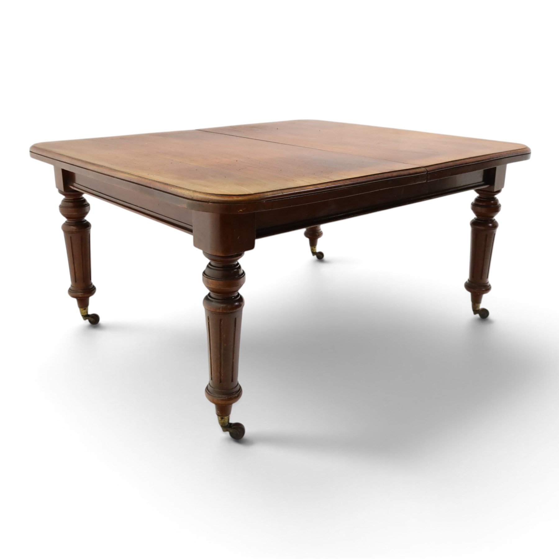 19th century mahogany extending dining table, rectangular top with rounded corners raised on turned and fluted supports with brass cups and castors, with two additional leaves; with set of eight (6+2) Regency design mahogany dining chairs, spiral-reeded back-bar over drop-in seats and sabre supports (W54cm H85cm)
