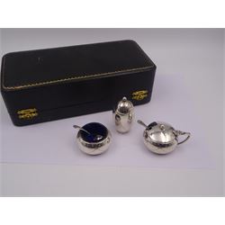 1950s silver three piece cruet set, comprising pepper shaker, open salt, mustard pot and cover, engraved with ribbon swags, hallmarked Joseph Gloster Ltd, Birmingham 1956, salt and mustard pots with blue glass liners, together with two condiment spoons, hallmarked, all within a fitted silk and velvet lined case 