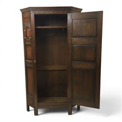 20th century dark stained oak hall robe, cantered sides enclosing a hooks and a shelf, panelled and carved sides, raised on stile supports