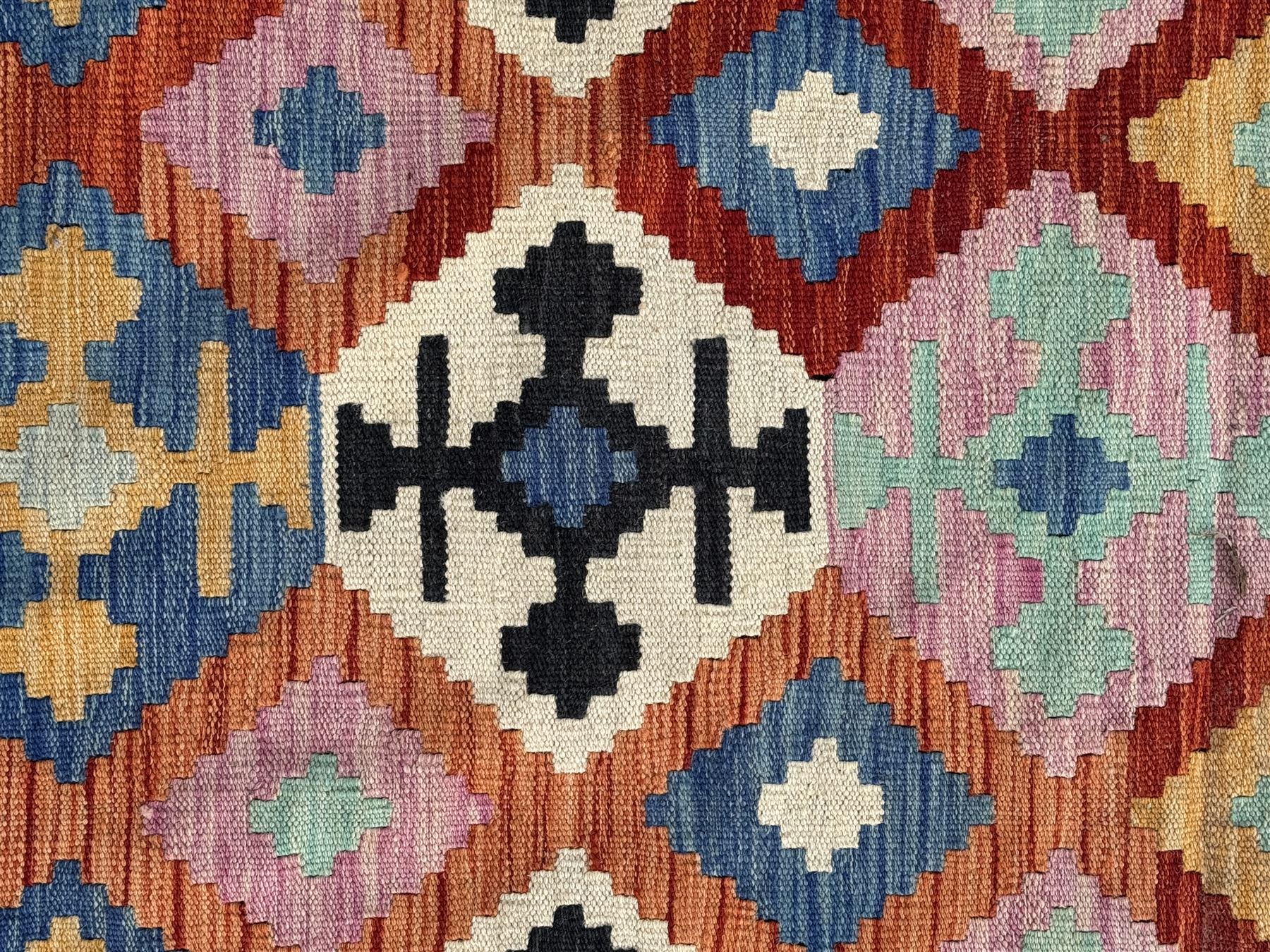 Kilim pastel ground rug, the field decorated with repeating multicoloured geometric diamond motifs, enclosed within matching geometric borders