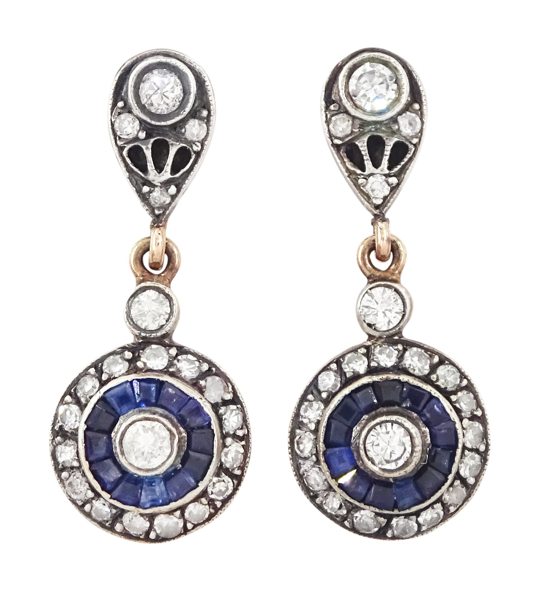 Pair of rose gold and silver diamond and sapphire pendant earrings, each stud set with a round brilliant cut diamond, surrounded by calibre cut sapphires and diamonds, suspending from a single diamond and pierced design diamond tops, total diamond weight approx 0.70 carat, total sapphire weight approx 0.50 carat