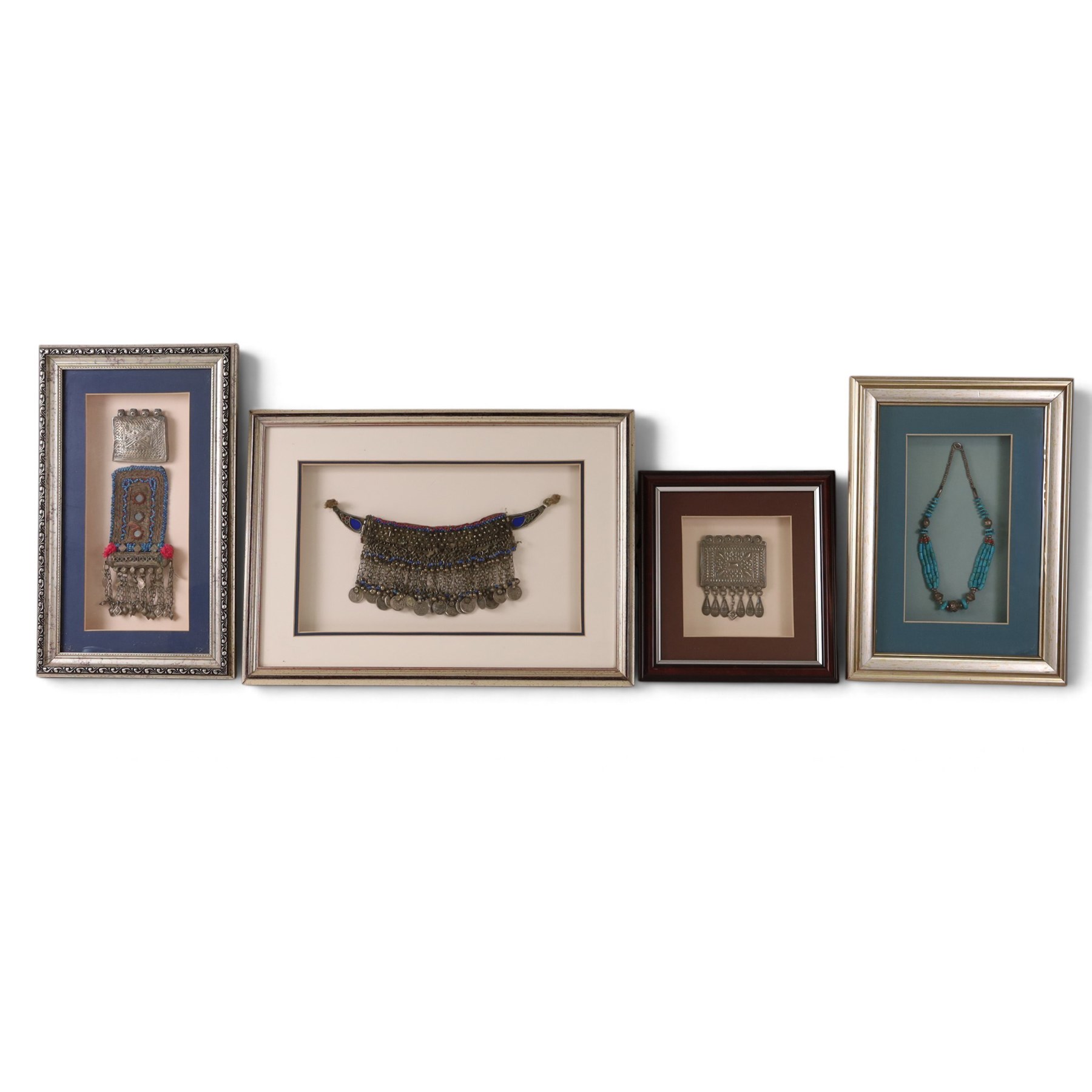 Four framed pieces of jewellery, including tribal coin and blue stone choker, multi stand necklace with turquoise beads and two box pendants 