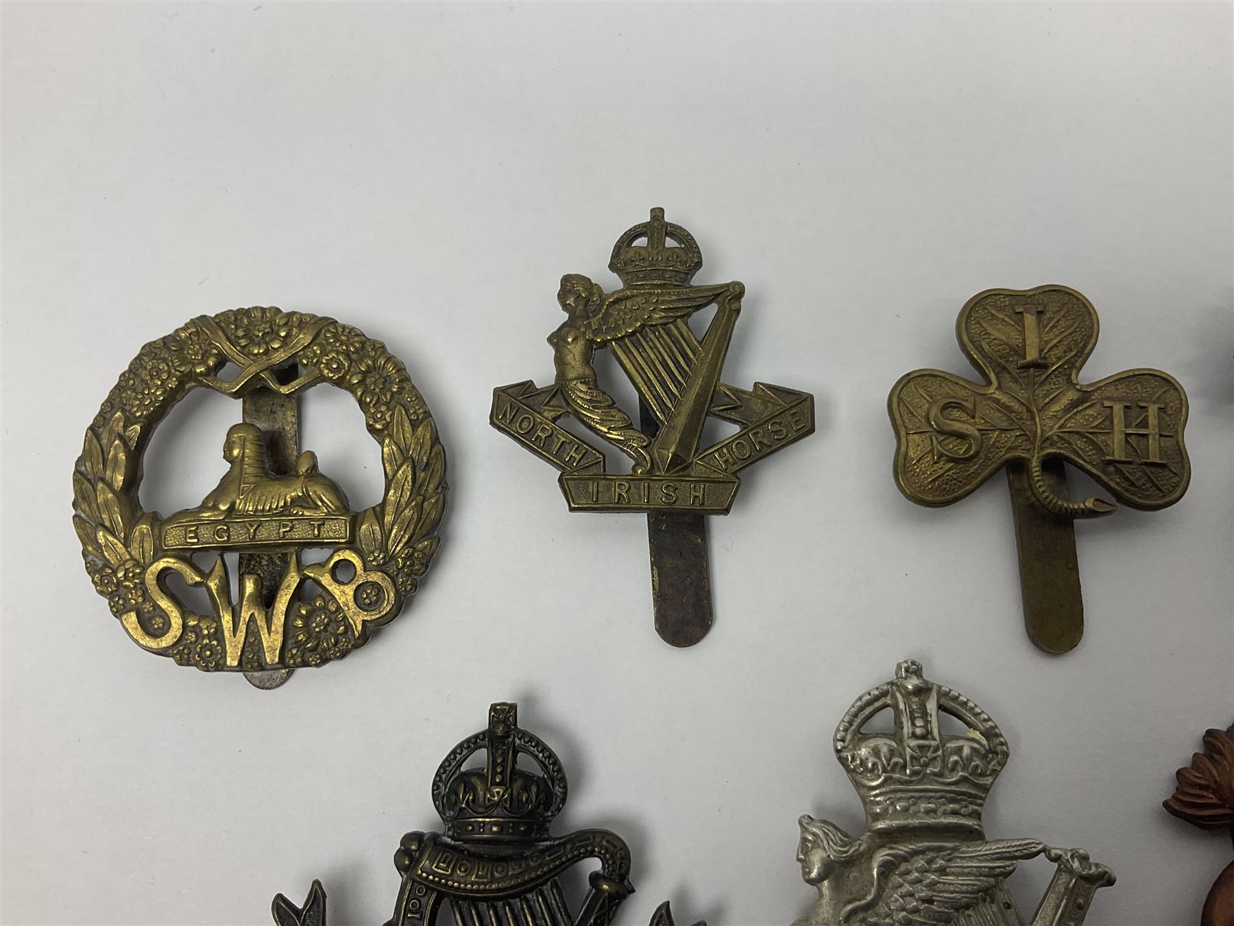 Fourteen cap badges of Irish interest including Royal Dublin Fusiliers inscribed to the slider 'From A. O'Connor 2nd Batt. Dec.2nd 1915', Connaught Rangers, South irish Horse Yeomanry, Inniskilling Fusiliers, Royal Irish Regiment etc; and seven Welsh badges including South Wales Borderers, Welsh Guards, 3rd Bn. Monmouthshire Regt. etc (21)