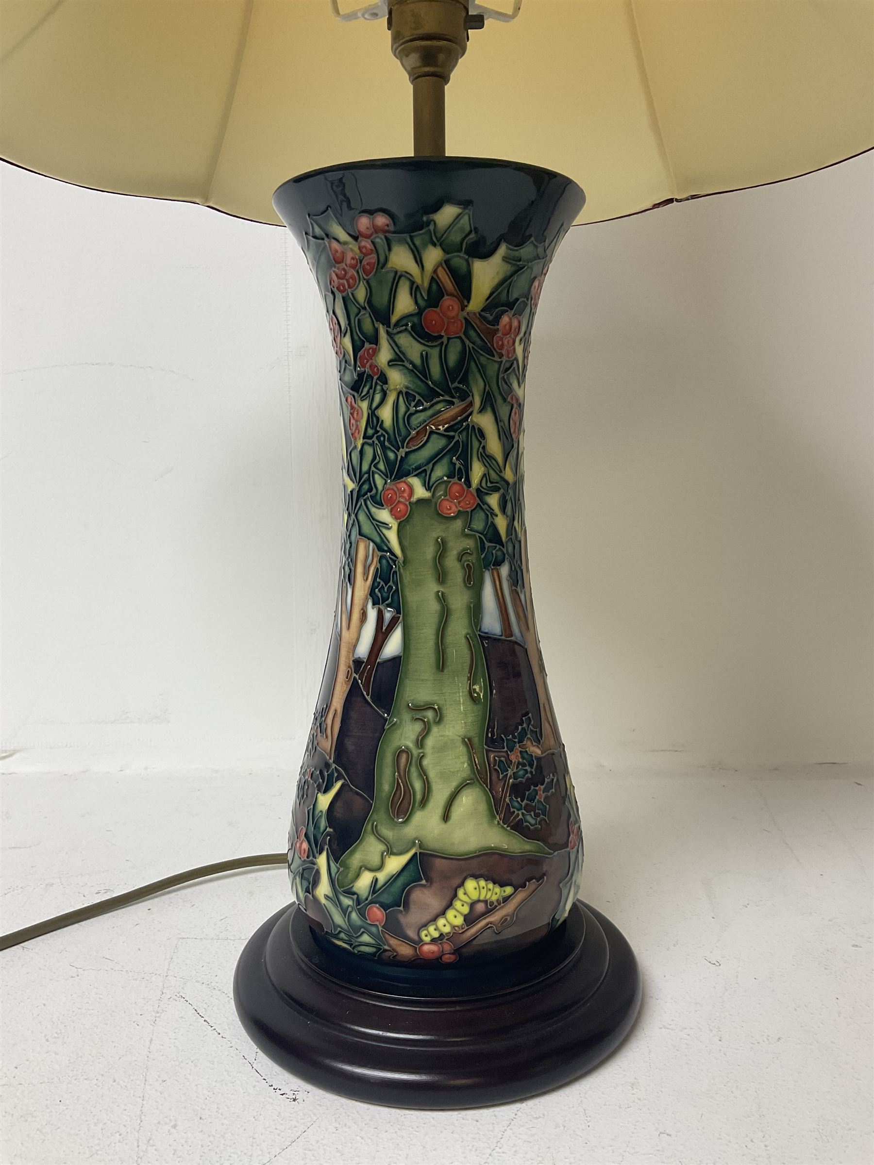 Moorcroft table lamp, of waisted form, decorated in the Holly Hatch pattern, on wooden plinth, with accompanying cream shade of lobed form, with piped detail, H33cm (excluding fitting)