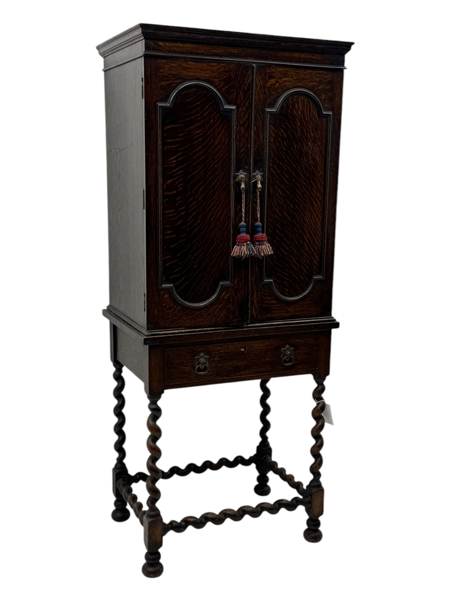 Early 20th century oak two-door cabinet, with single drawer, interior with four fixed shelves on raised barley twist stand 
 