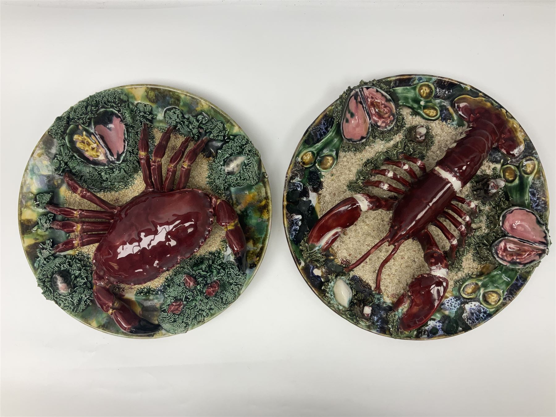 Two 20th Century Portuguese Palissy style Majolica wall plates, one depicting a crab, the other a lobster each to the centre modelled in relief surrounded by encrustations and shells, both with impress marks beneath, D34cm