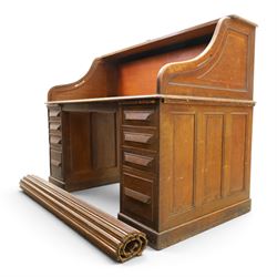 Cutler - Late Victorian oak pedestal tambour desk, the tambour shutter enclosing fitted interior, pull-out writing surface over central kneehole flanked by two pedestals each fitted with four drawers with moulded fronts, pull-out slides above, panelled sides, on moulded plinth base