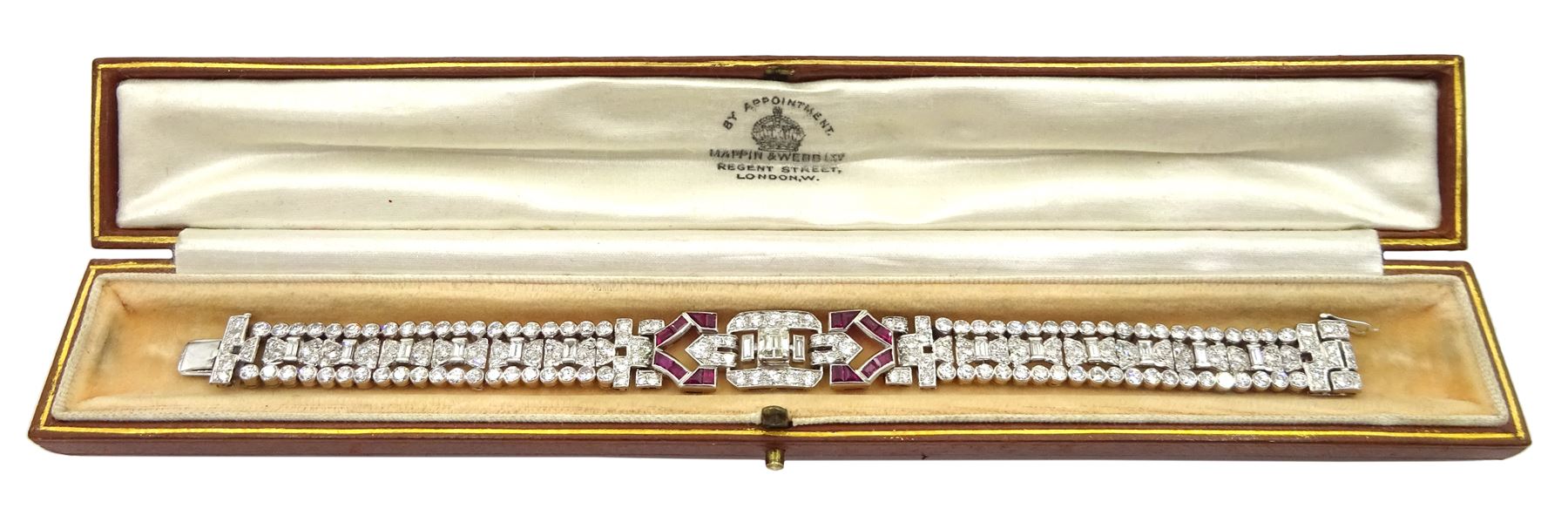 Art Deco platinum diamond and ruby bracelet, circa 1920-1930, the central panel set with a single emerald cut diamond of approx 0.55 carat, flanked by two baguette cut diamonds and old cut diamond surround, the articulated geometric design bracelet with vari-cut rubies, round and baguette cut diamonds, total diamond weight approx 7.00 carat, in Mappin & Webb silk and velvet lined box