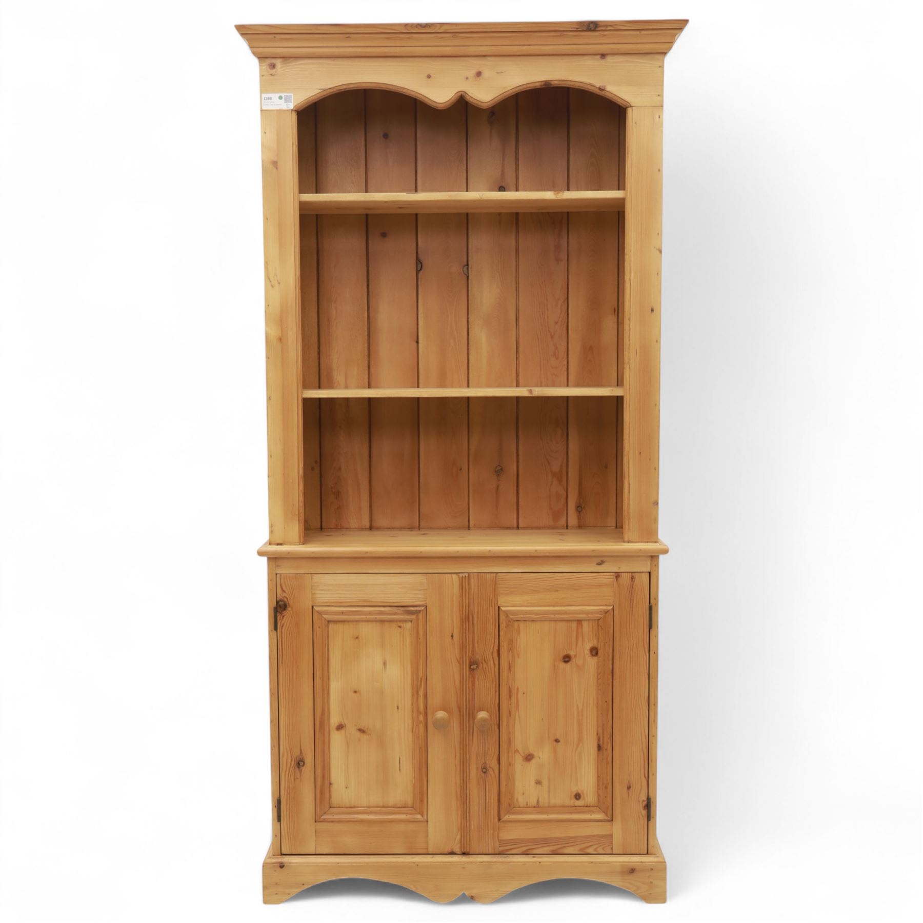 Contemporary pine kitchen dresser, moulded cornice over open plate rack with shaped frieze and two fixed shelves, enclosed lower section with panelled twin doors and shaped plinth base