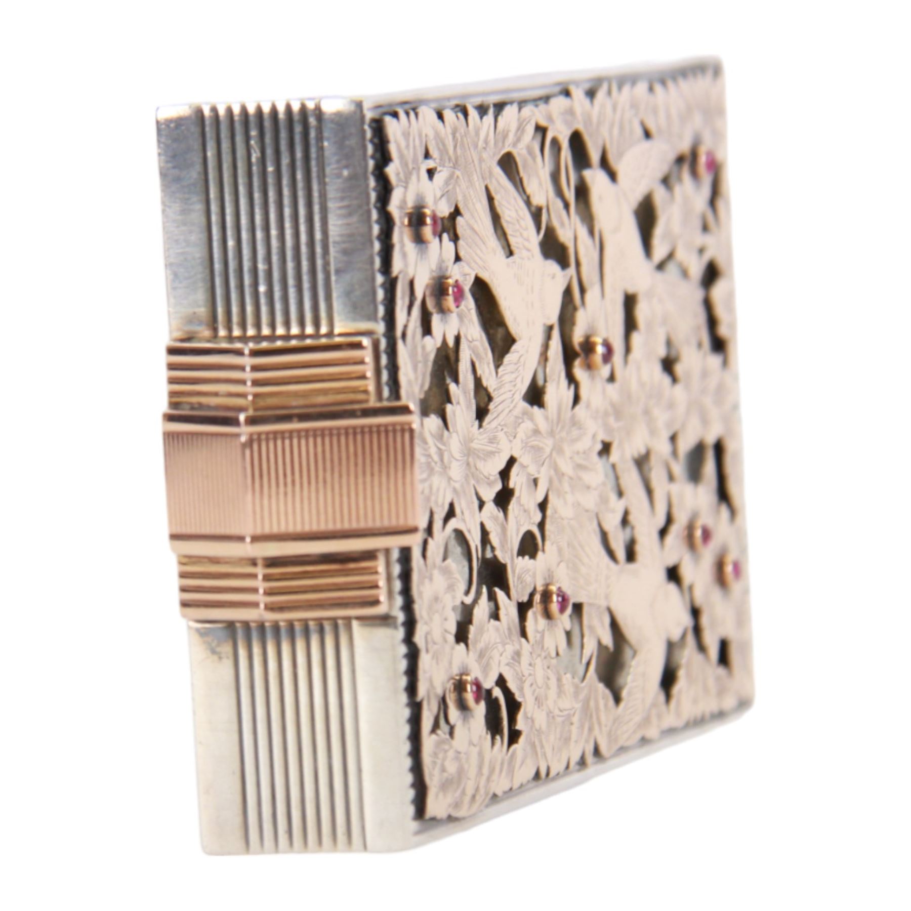 Mid 20th century French silver and gold vanity case, of rectangular form, the hinged cover decorated with an openwork panel of bids and cabochon ruby studded flower heads, opening via a pull clasp to reveal a mirror to the underside and compartment with lift up cover, signed J. Lacloche Paris Cannes, and bearing French assay marks, not including clasp L10cm W6cm D1.5cm

