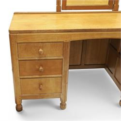 Mouseman - adzed oak kneehole dressing table with mirror, the rectangular adzed top with raised back and canted corners with fixed central pivoting mirror with scallop-carved cresting rail, over an arched recessed kneehole flanked by three graduating drawers to each side with turned knob handles, raised on octagonal feet, with carved mouse signature, by the workshop of Robert Thompson of Kilburn