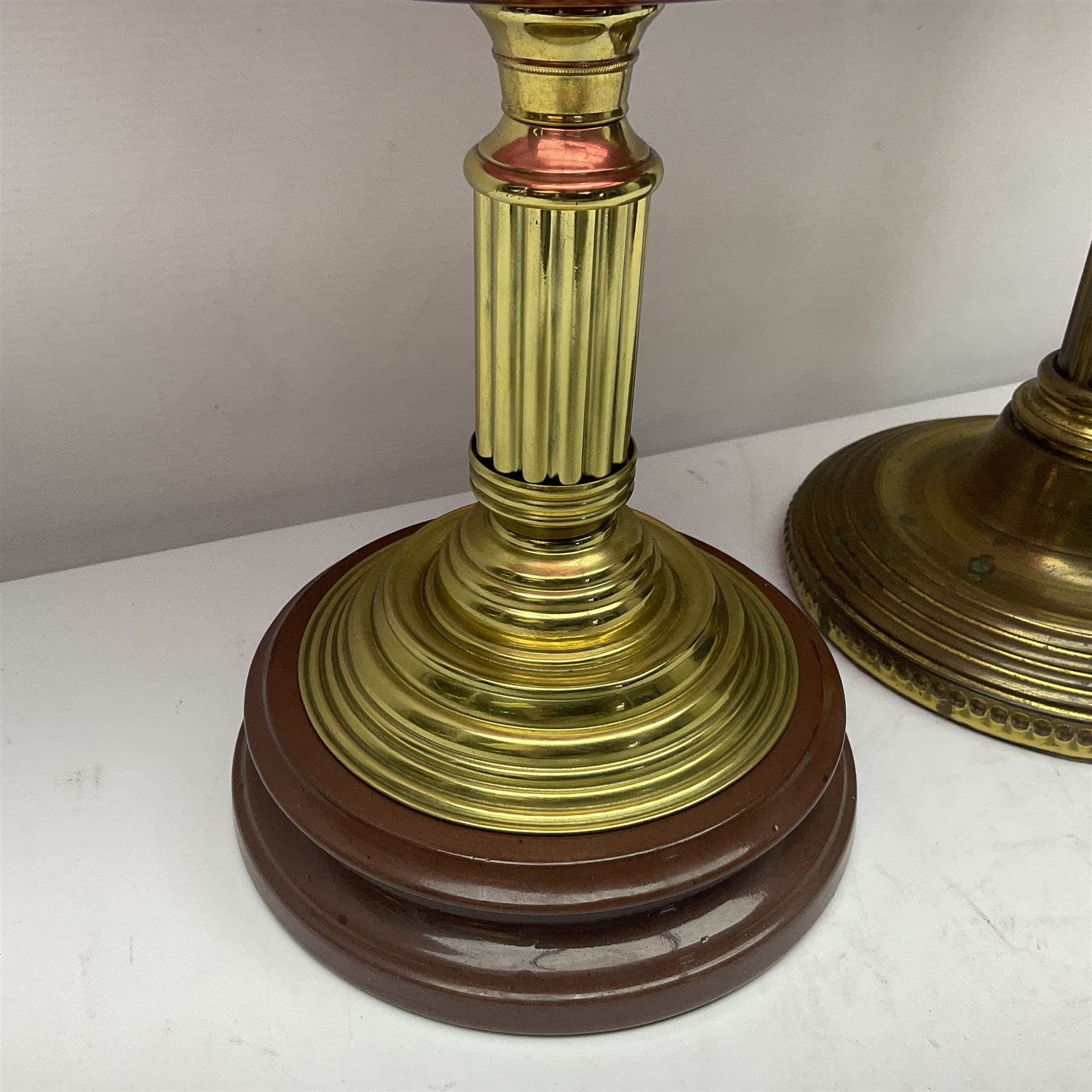 Victorian cast brass oil lamp, with fluted pink glass shade, together with two smaller brass oil lamps with pink shades and reservoirs and a pair of oil lamps, the bases modelled as putti, with pink glass reservoir  and frosted shades, tallest H70cm