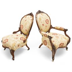 Victorian Ladies and Gentleman's carved walnut drawing room chairs, each with shaped cresting rail carved with scrolls and flowerheads, upholstered in pale gold floral fabric, raised on foliate-carved cabriole supports terminating to brass and ceramic castors