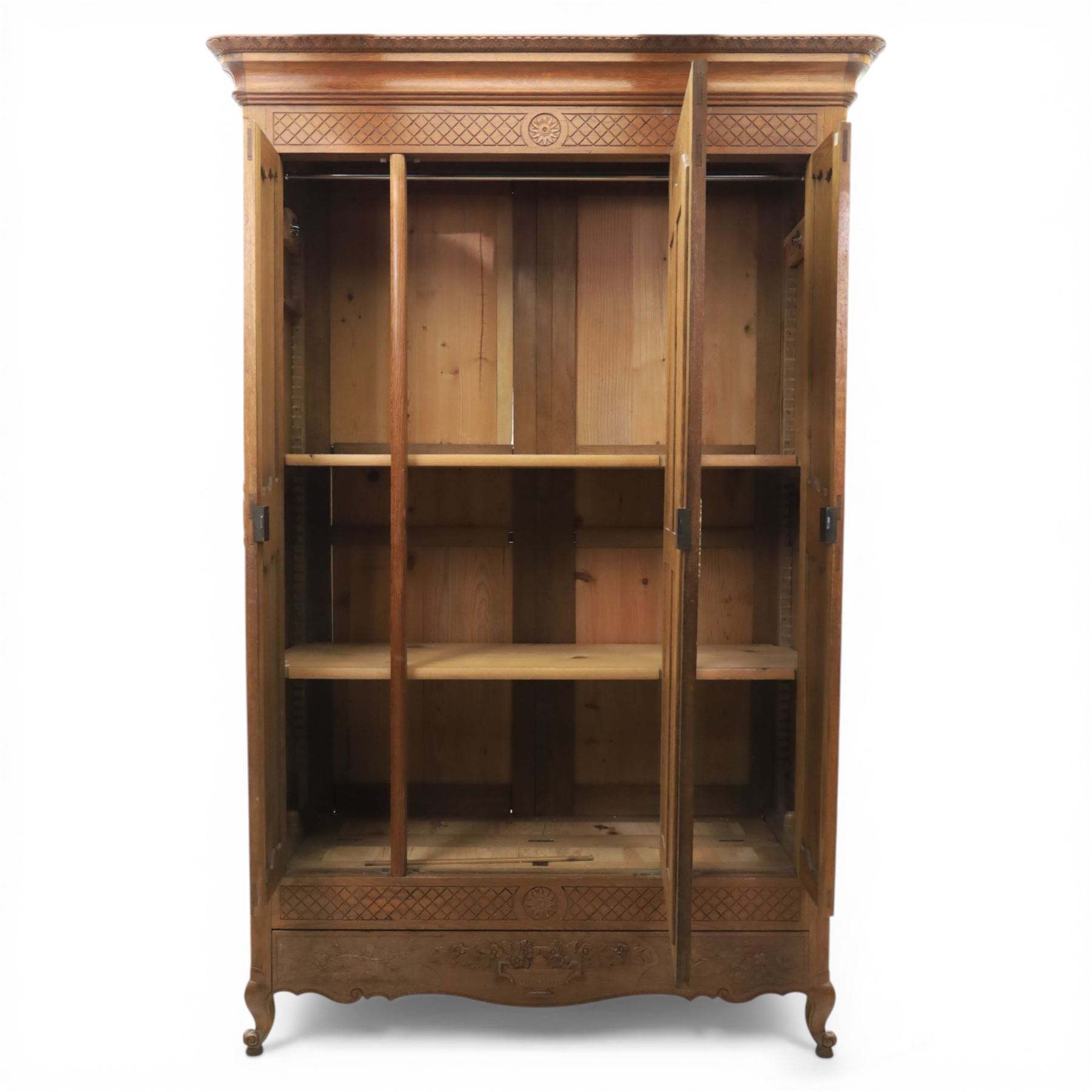 Early 20th century French oak triple door armoire, the moulded top above a frieze with carved lozenge decoration and central rosette, the central mirrored door enclosed by carved surround with floral crest, flanked by panelled doors with lattice carving, the base with shaped apron centred by carved basket motif, upon shaped cabriole supports