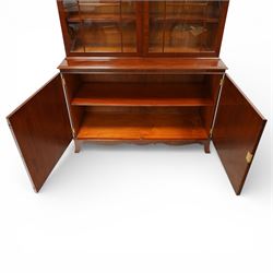 William Tillman - Early 20th century mahogany display cabinet, moulded cornice above a frieze carved with roundels and fluting, pair of astragal glazed doors enclosing adjustable shelving, the lower section fitted with twin panelled cupboard doors centred with oval veneered panels, shaped apron and bracket feet