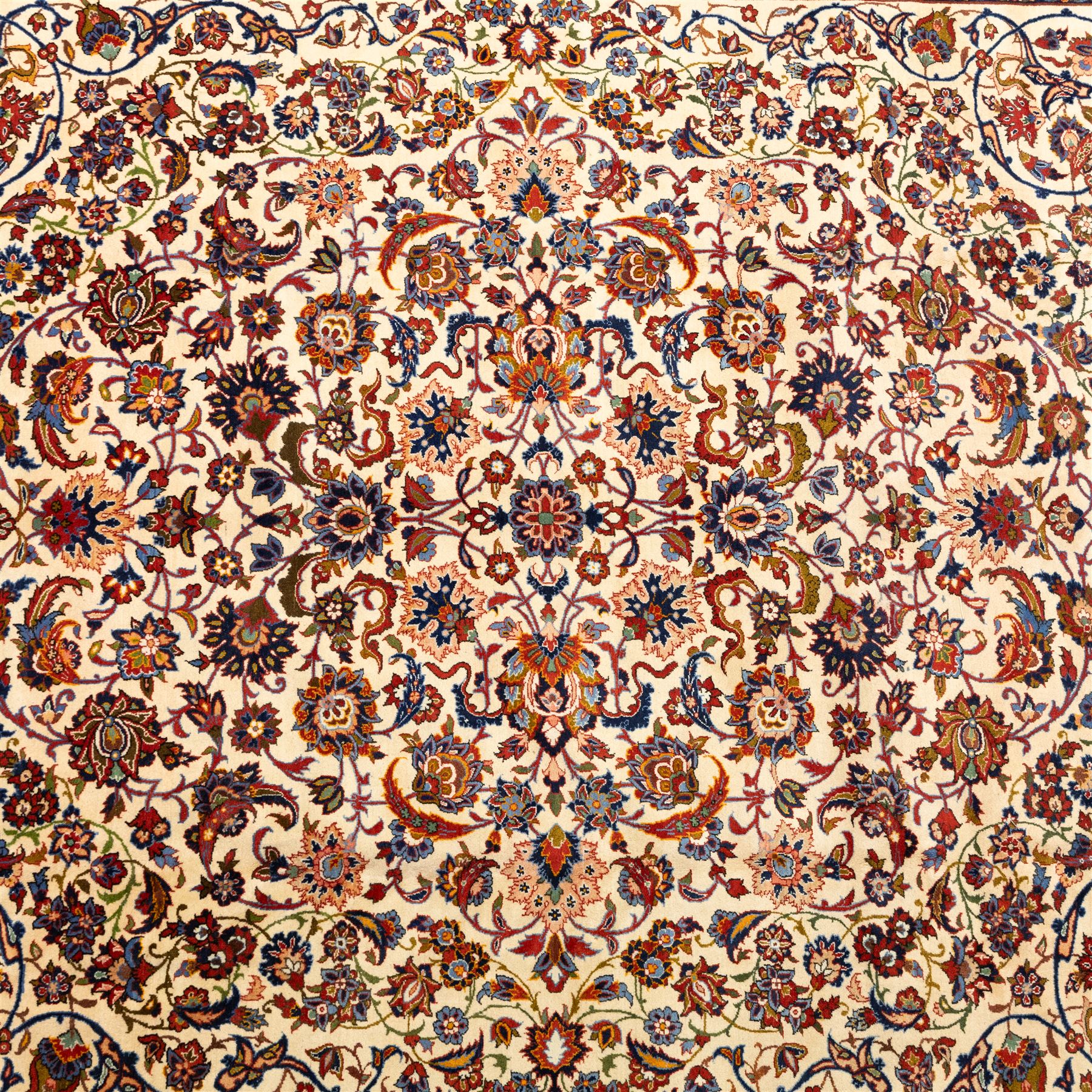 Central Persian Najafabad hand-knotted carpet, ivory field with an all-over scrolling floral design of palmettes, rosettes, and leafy vine work, enclosed by a wide floral main border flanked by multiple guard borders in madder red, indigo blue, green, and pale ochre, with cotton fringe ends 