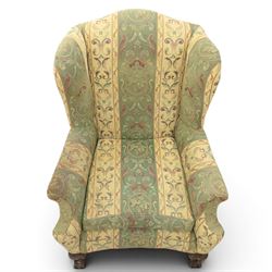 Queen Anne style wingback armchair, upholstered in green and cream foliate fabric, shaped arms on ball and claw feet