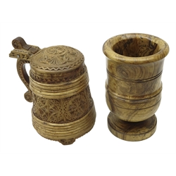  20th century Norwegian Peg Tankard, tapering staved body and lid carved with geometric roundels, scroll hinged handle and three shaped feet, H20cm and a turned walnut footed vessel (2)  