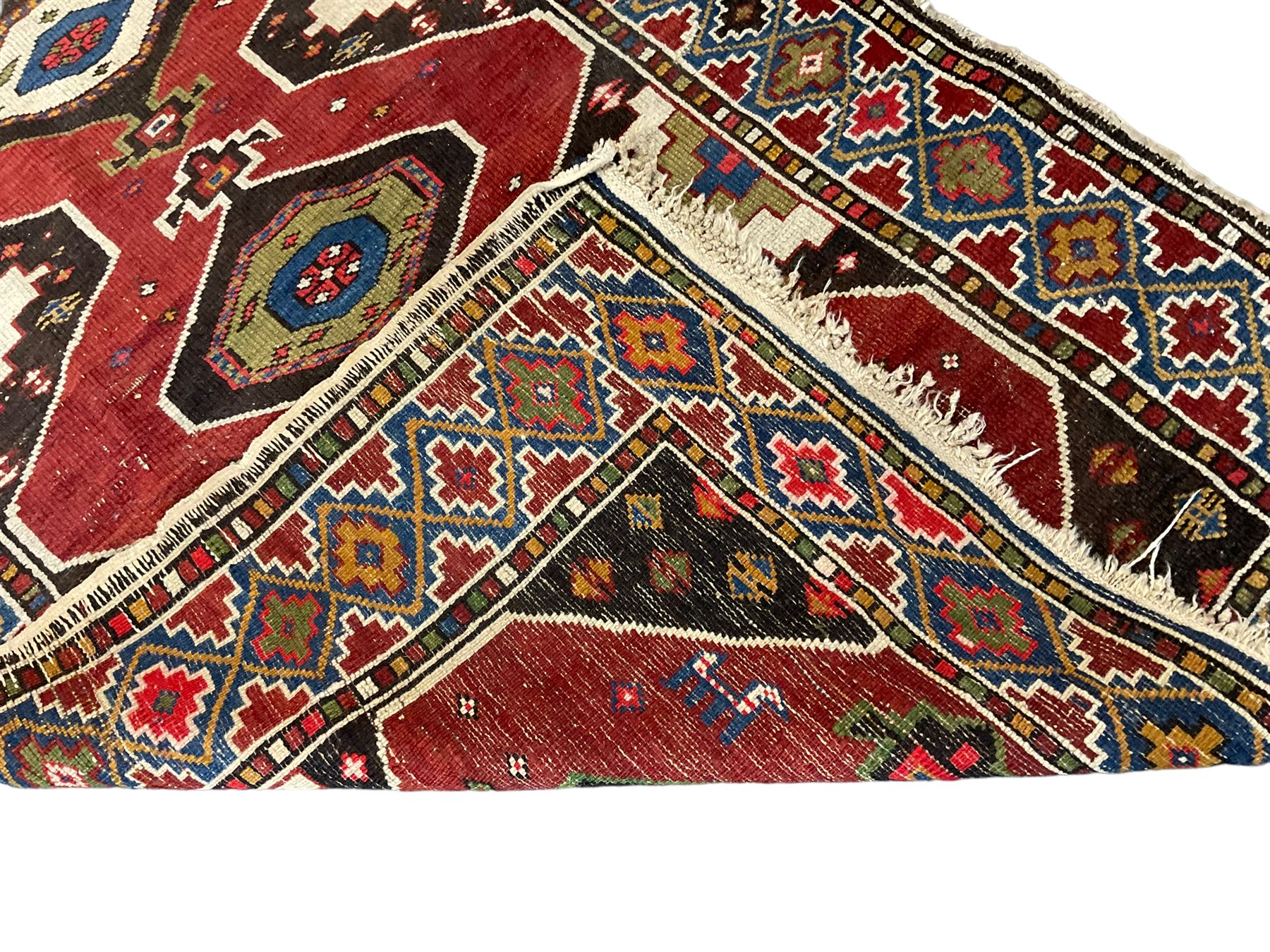 Anatolian Turkish red ground rug, decorated with three central lozenges, the multi-colour guarded border with repeating geometric shapes