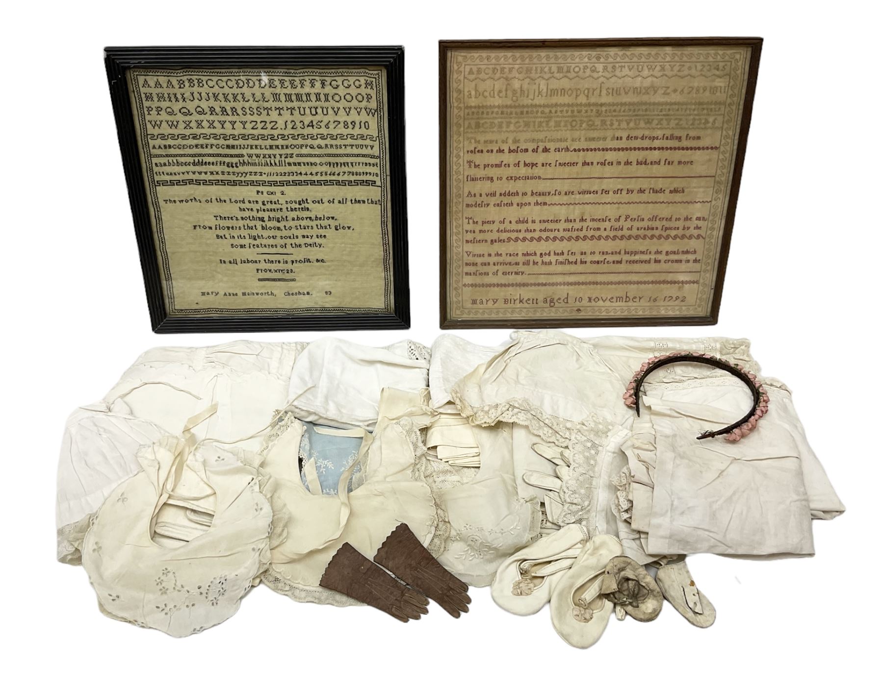 Late 18th century sampler worked with the alphabet above verses in red, by Mary Birkett aged 10 November 16th 1792, H33.5cm W34.5cm, together with another sampler worked with the alphabet above Proverbs 14:23, by Mary Anne Hainworth, Chesham, date unknown (--83), both in glazed frames, together with a quantity of Victorian and later dolls clothes to include lace examples