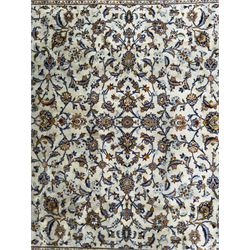 Central Persian Kashan hand-knotted carpet, the ivory ground intricately decorated with scrolling vines, palmettes, and stylised flowerheads in soft blue, gold and brown tones, enclosed by a broad indigo border with repeating floral motifs and multiple guard stripes
