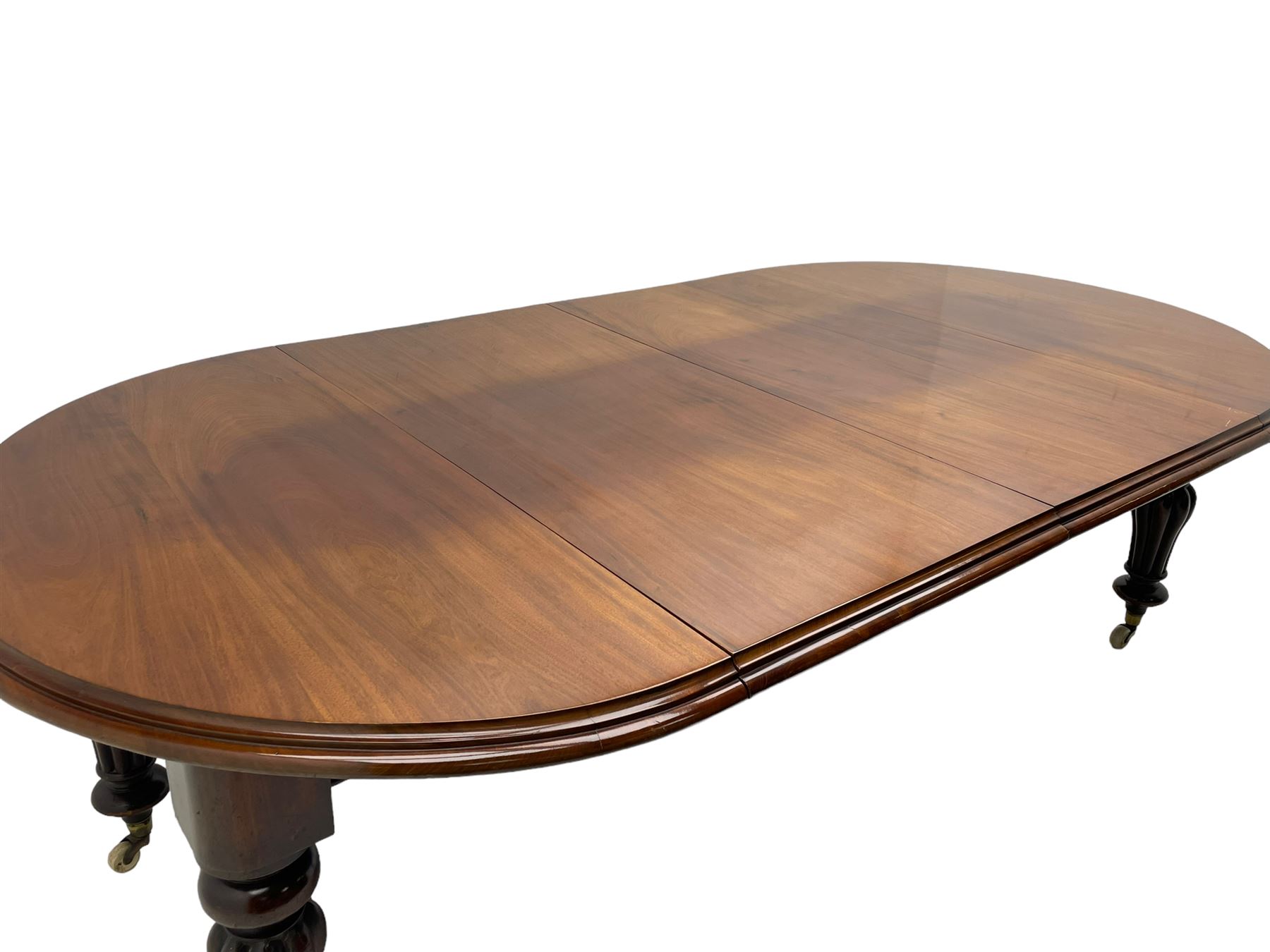 Victorian mahogany extending dining table, circular telescopic extending top with moulded edge, two additional leaves, on turned and lobe carved supports with brass and ceramic castors 