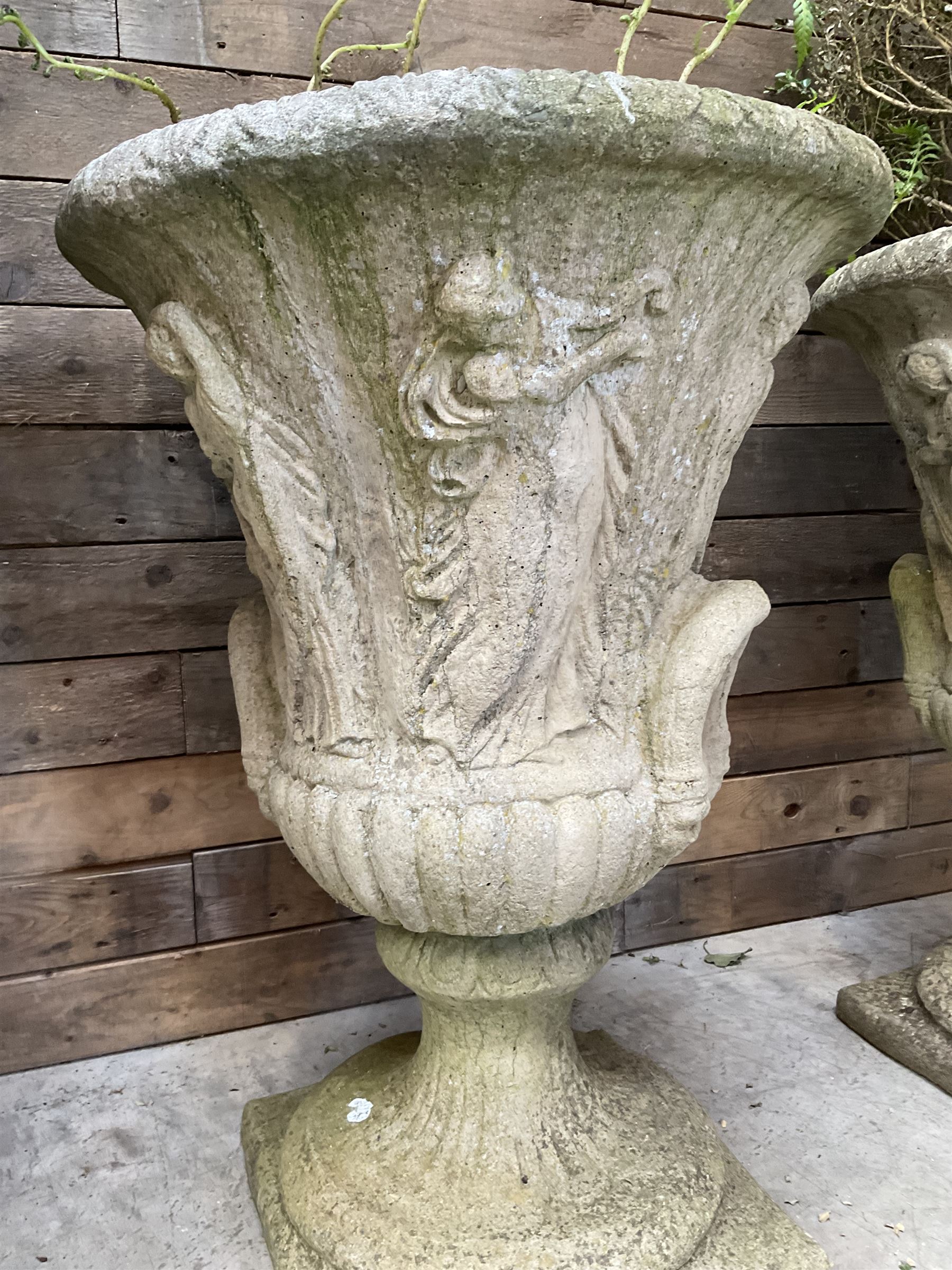 Set of four Victorian design cast stone Grecian urns, tapering form cast with figures and handles, square plinth bases