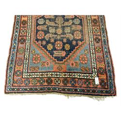 Old Persian rug, the field with two interlinked indigo ground medallions decorated with Herati motifs, the border decorated with repeating stylised flower head motifs within guard stripes